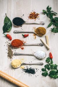 Spoons laid our horizintally with various dried herbs, green herbs around on white countertop, korean vegan recipes