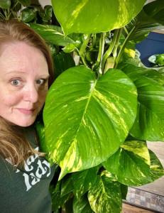 Plant People Boutigue owner Sarah Buchanan next to a giant-leafed plant.