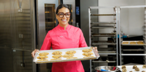 Maya, holding her vegan cookies on a baking tray. Unique gifts that inspire.